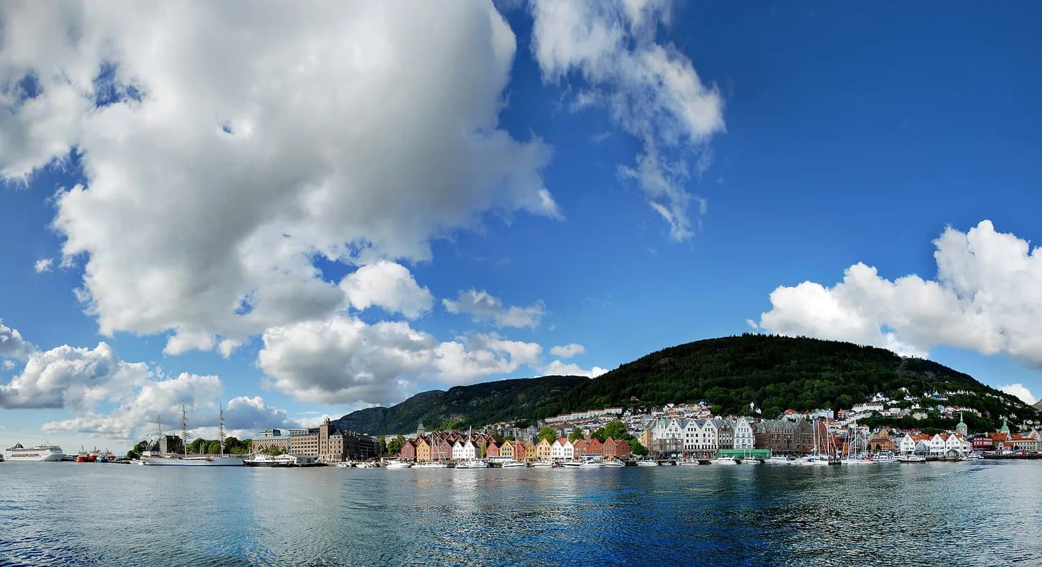 Bryggen i Bergen sett over Vågen, med fjell og skyer bak