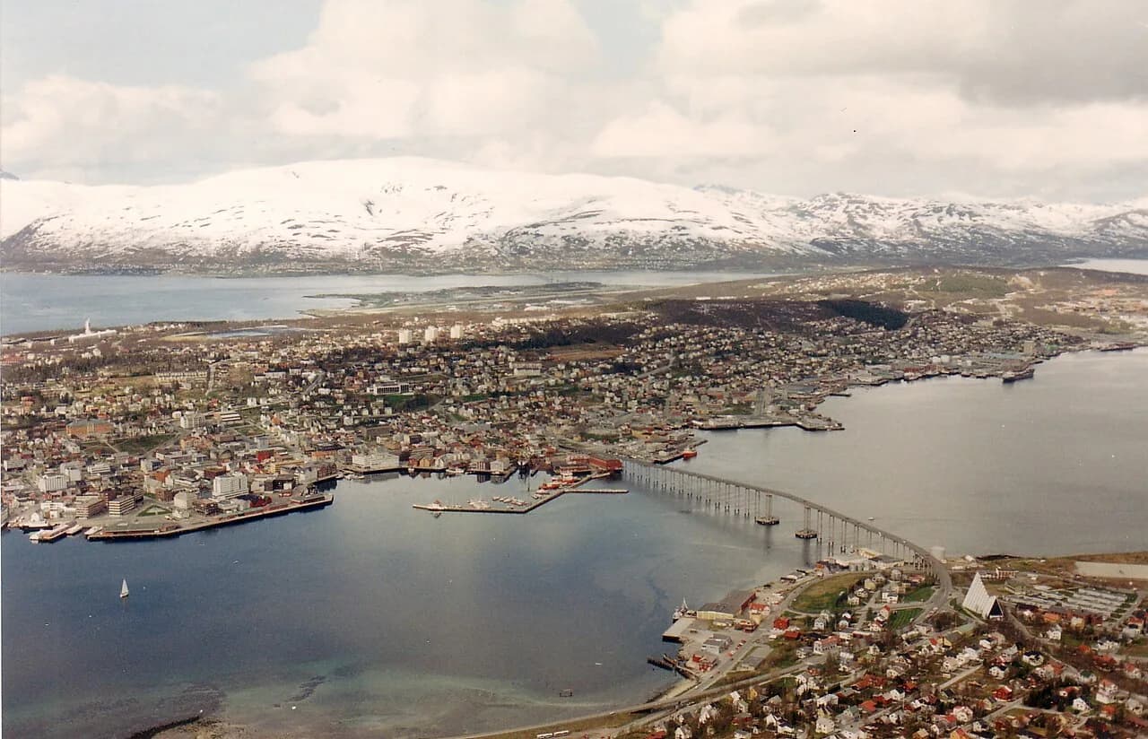 Tromsø med bro, sjø og snødekte fjell sett ovenfra